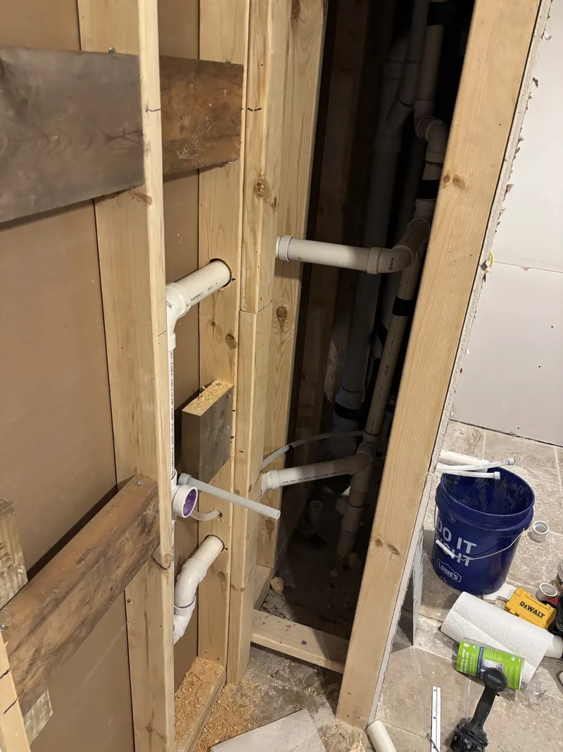 Water and drain piping roughed in through open wall framing for a drinking fountain.