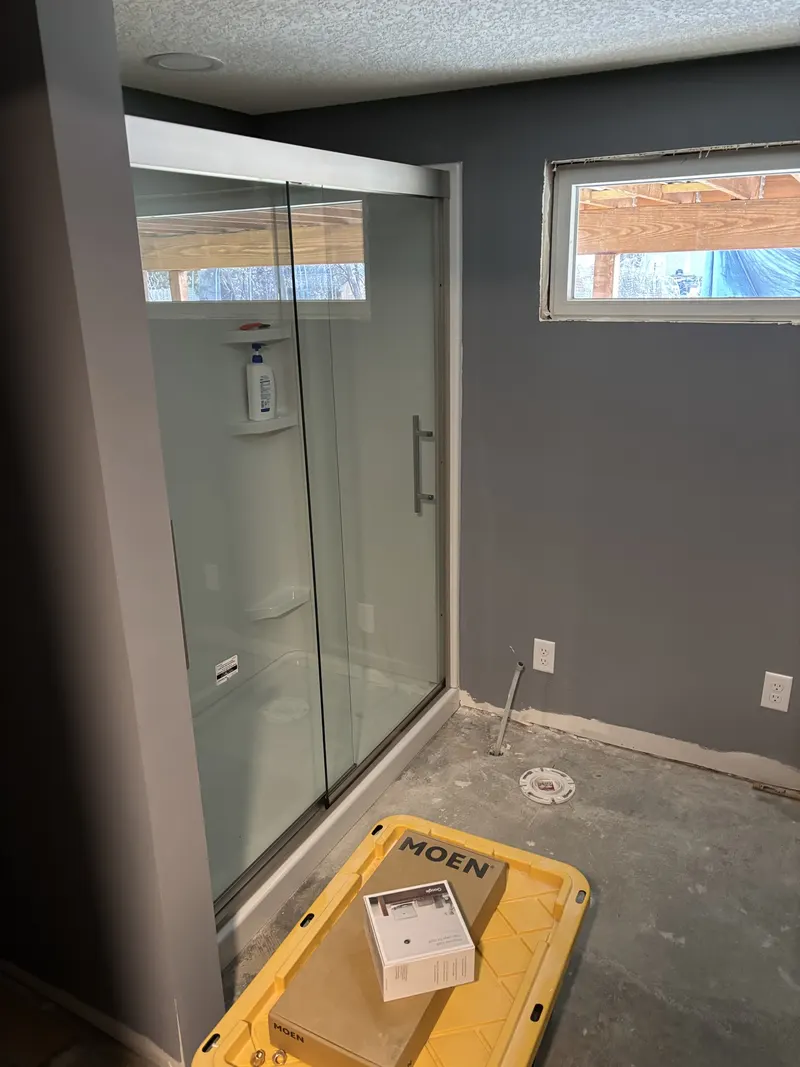 Completed tiled shower with a glass enclosure and installed plumbing trim.