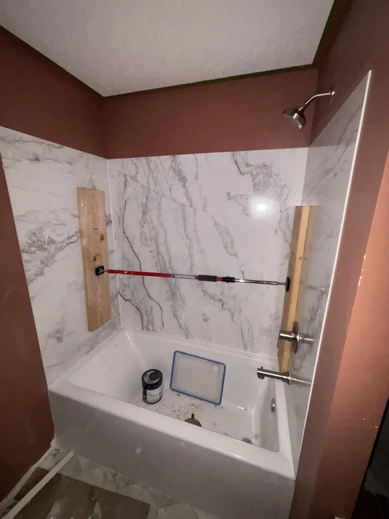 Shower valve and wall-mounted body-spray rough-in visible before tile installation.