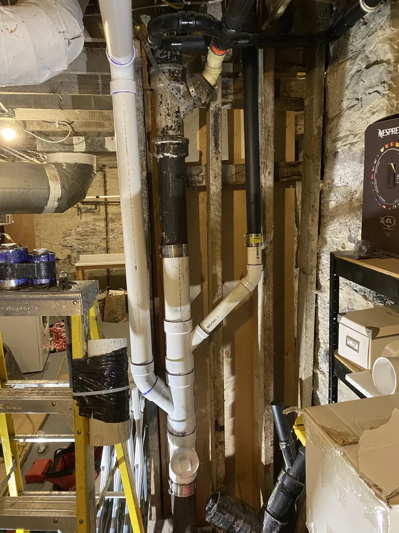 Multiple water, drain and vent lines visible inside opened wall framing.