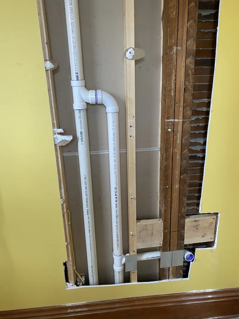 New water-supply and drain piping routed through an opened wall cavity.
