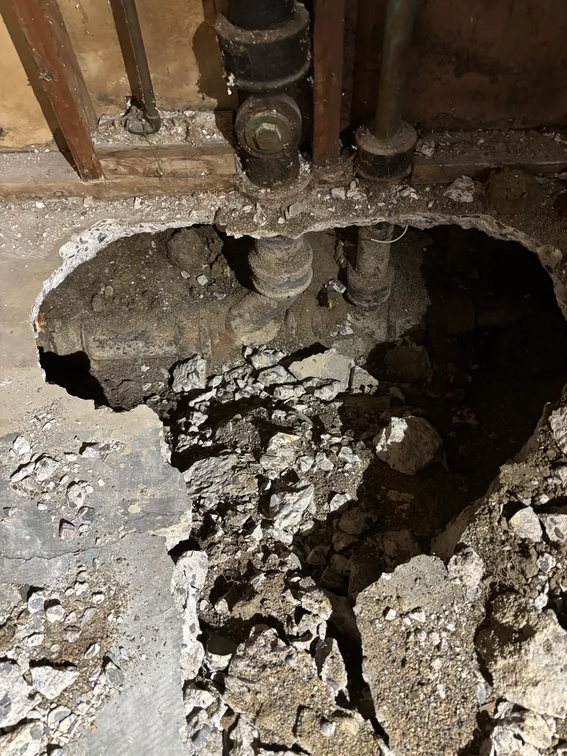 Concrete floor opened around existing underground drain piping.