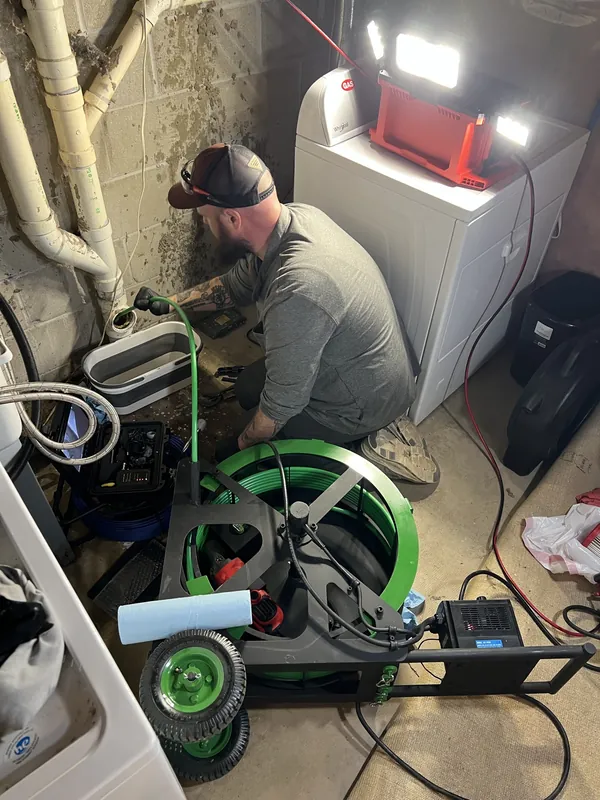 Plumber operating a drain cleaning cable machine