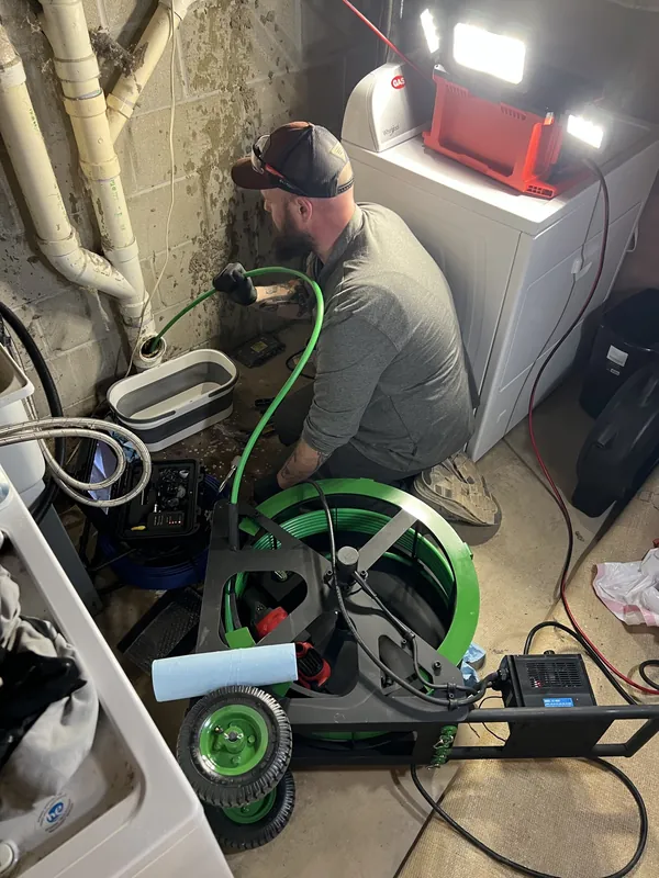 Drain cleaning cable machine and inspection camera set up for a basement floor drain job