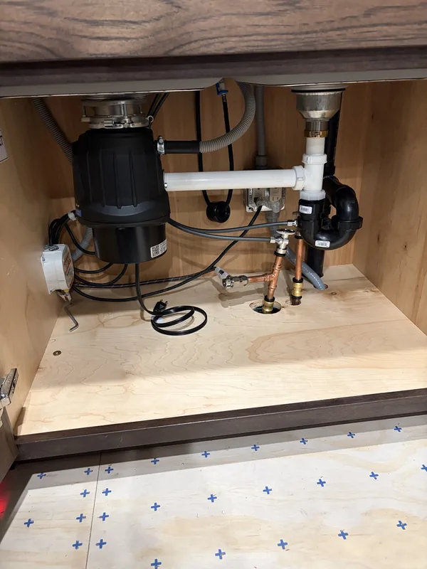 New garbage disposal and drain trap assembly installed under a kitchen sink