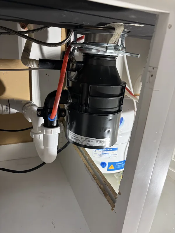 Garbage disposal mounted under a kitchen sink during installation