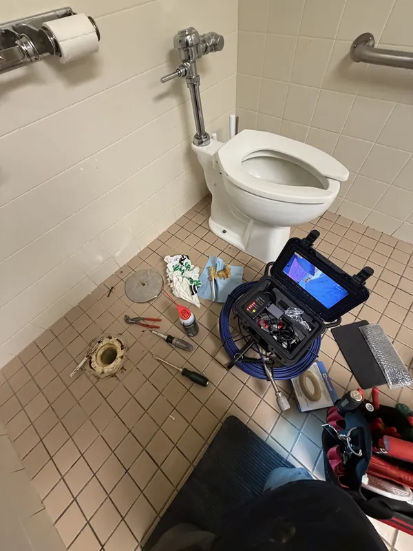 Sewer inspection camera reel and monitor set up next to a toilet for a line inspection