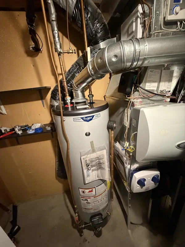 New gas water heater installed with updated copper piping and venting in a mechanical room